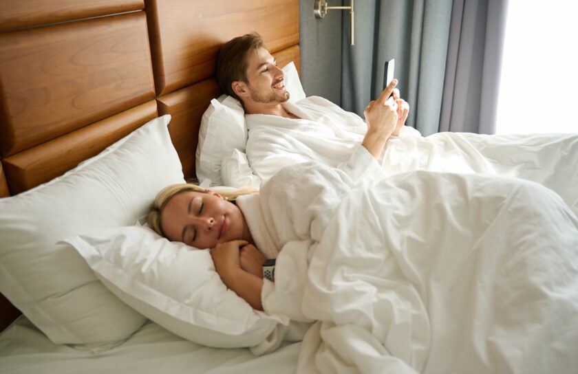 guy-with-a-mobile-phone-is-resting-on-a-large-bed-2024-10-18-08-41-46-utc