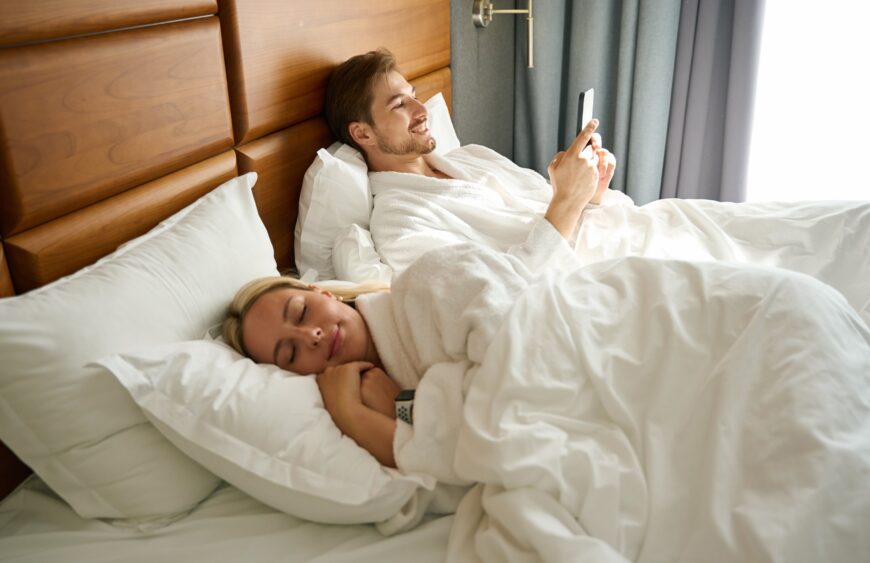 guy-with-a-mobile-phone-is-resting-on-a-large-bed-2024-10-18-08-41-46-utc