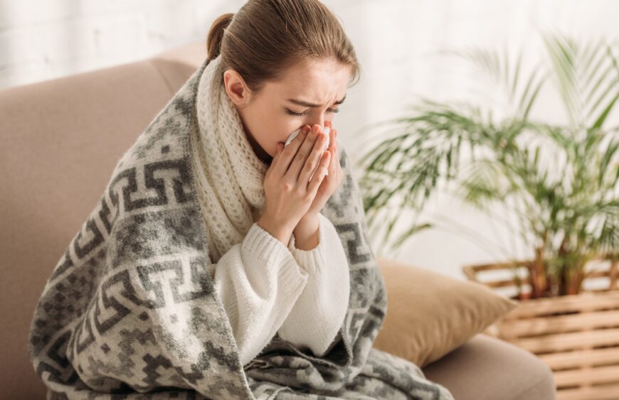 sick-woman-sneezing-in-napkin-while-sitting-on-sof-2024-11-09-11-34-02-utc